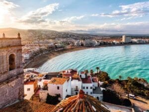 "Dramatic panoramic view of a Spanish mountain lake surrounded by wild vegetation and rocky cliffs, showcasing the natural beauty of rural Spain"