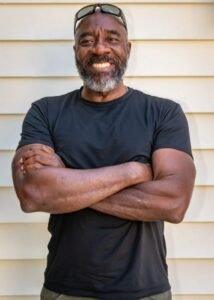 Moses West smiling confidently, wearing a black t-shirt, representing his role as the innovator of Atmospheric Water Generators and a leader in sustainable water solutions.